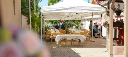 Kültéri rendezvényhelyszín sátrakkal, megterített asztalokkal és vendégváró hangulattal.