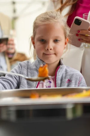 Kislány ételt szed a svédasztalról egy családi rendezvényen